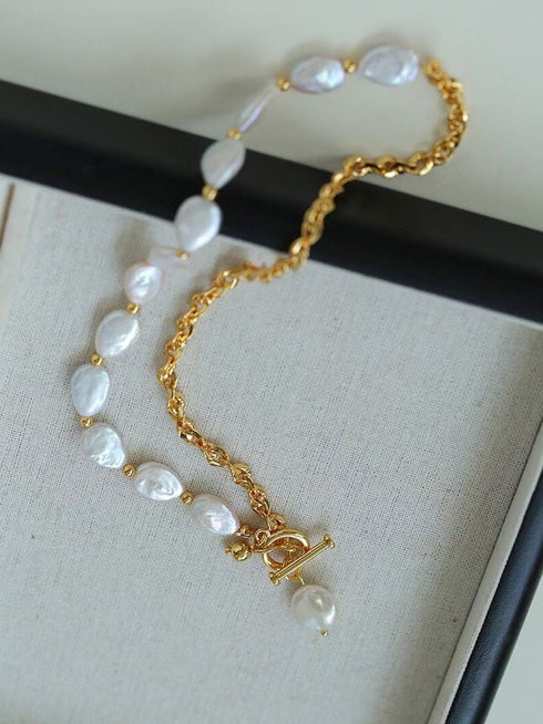 A gold chain necklace with irregular white baroque pearls and a toggle clasp
